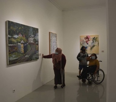 foto pengguna kursi roda dan pengguna tongkat melihat-lihat lukisan diruang pamer galeri R.J. Katamsi